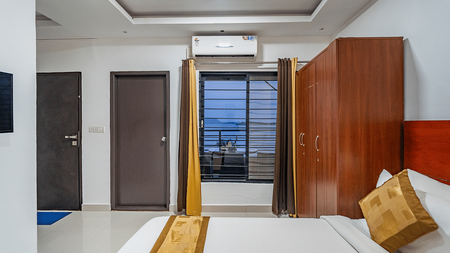 Side view of a room with bed and a window on the side with the curtains  open at Coorg Jungle Camp Backwater Resort, Kushalnagar.