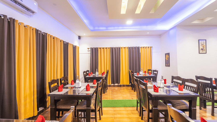 Image of a dining space with tables and chairs and windows on the side at Coorg Jungle Camp.