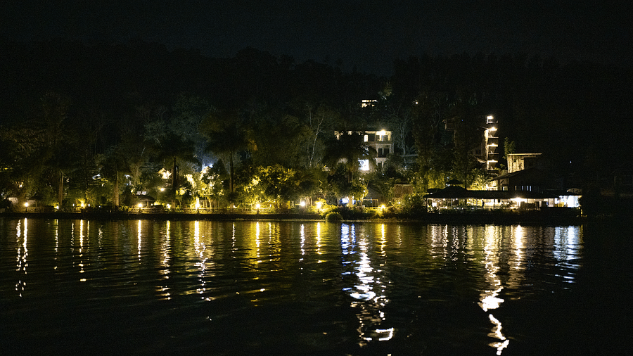 Night view of Coorg Jungle Camp with lights reflecting on the waterbody.