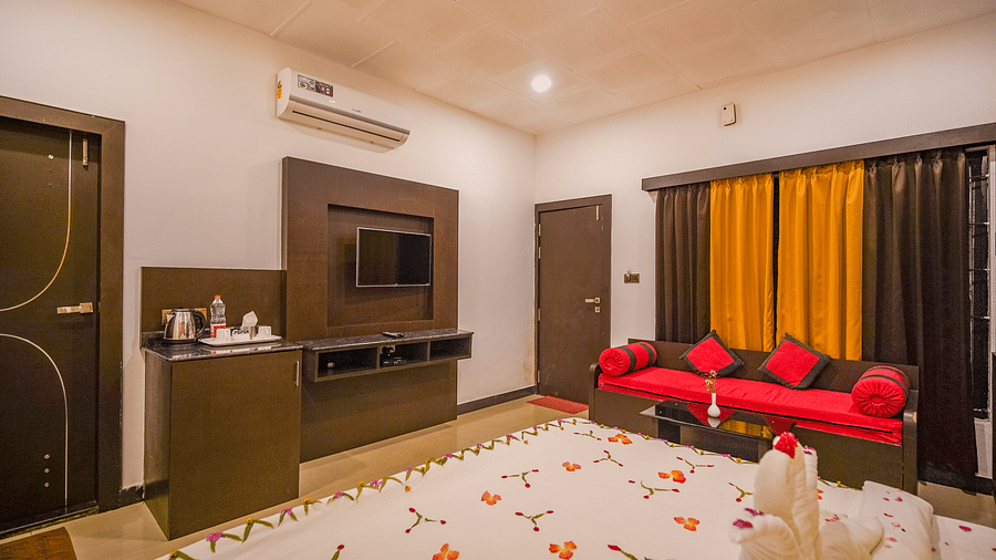 Image of a room with a bed decorated with flowers and a sofa in the corner at Coorg Jungle Camp.