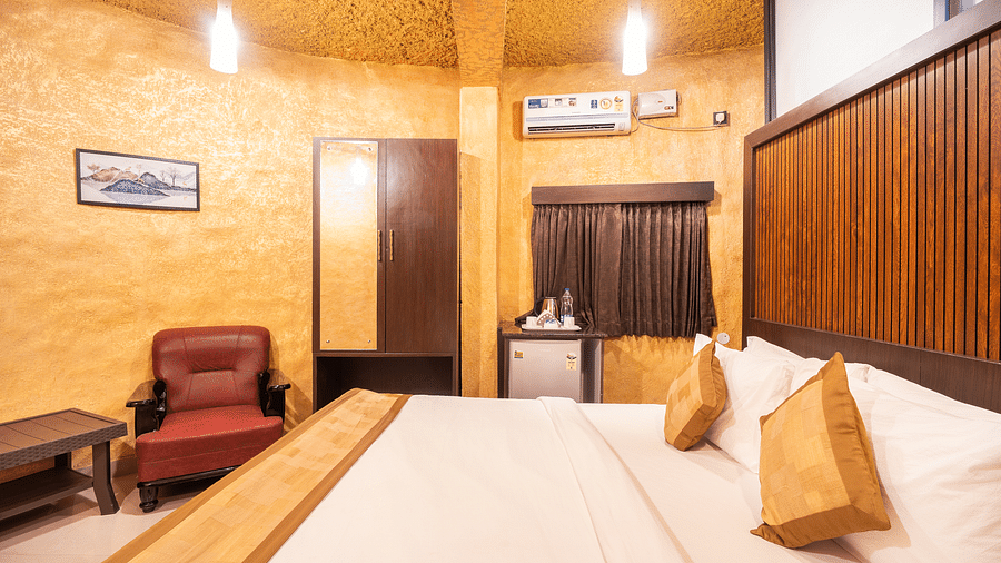 A room with a bed and a chair on the side at Coorg Jungle Camp Backwater Resort, Kushalnagar.