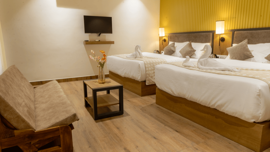 Bright bedroom suite showing a wooden couch, small coffee table, and large double bed against a yellow wall.