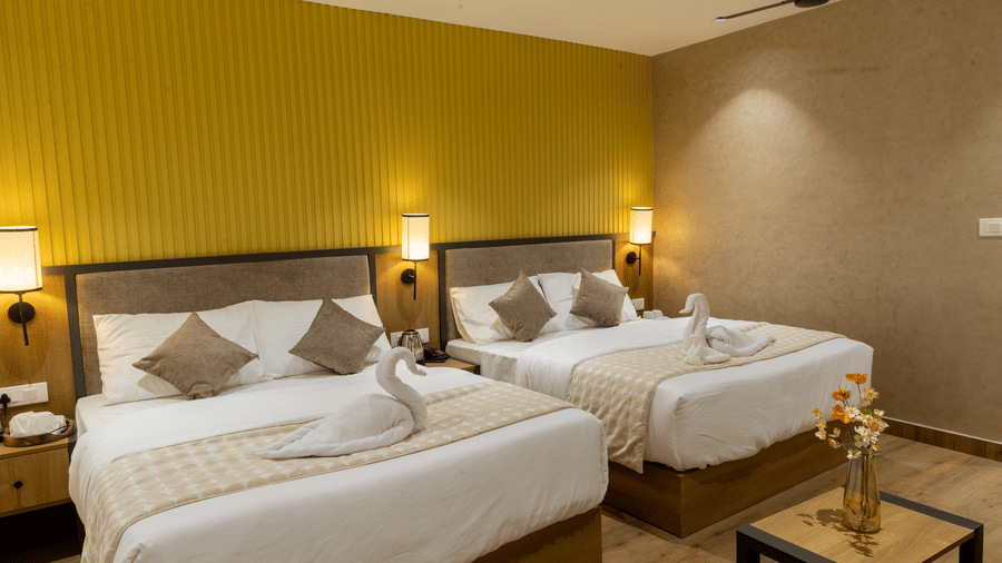 Modern hotel guest room showing two comfortable beds, ambient lighting, and neutral decor.