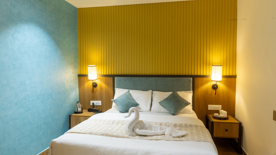 Symmetrical view of a hotel bed with matching bedside tables, teal wall accents, and warm ambient lighting.
