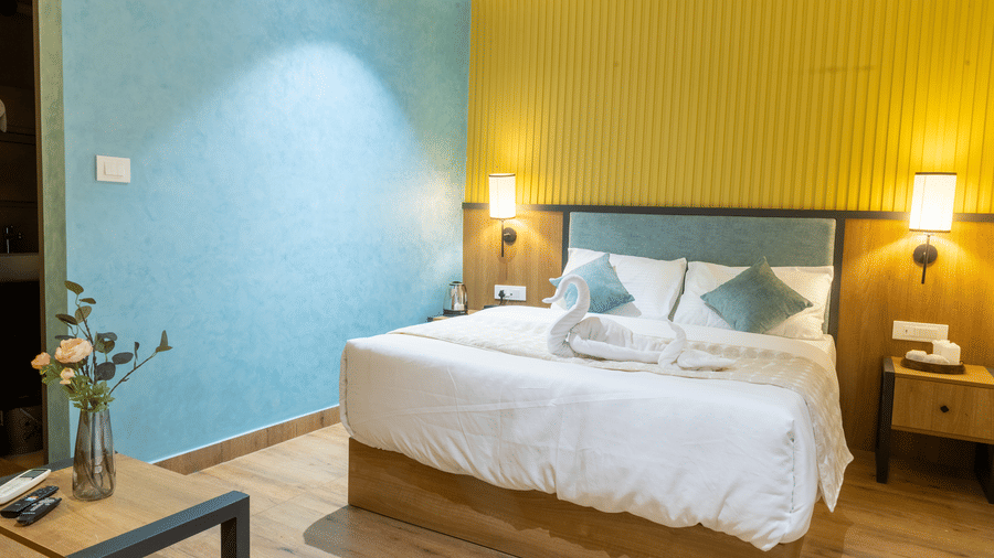 Contemporary guest suite featuring a king-sized bed, teal accent wall, yellow panelling, and bedside tables.