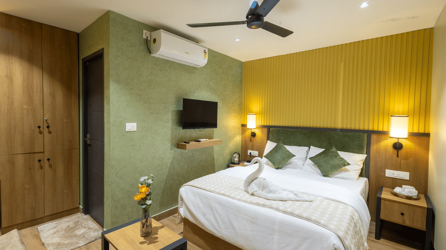Well-appointed hotel bedroom complete with air conditioning, ceiling fan, wooden wardrobe, and double bed.
