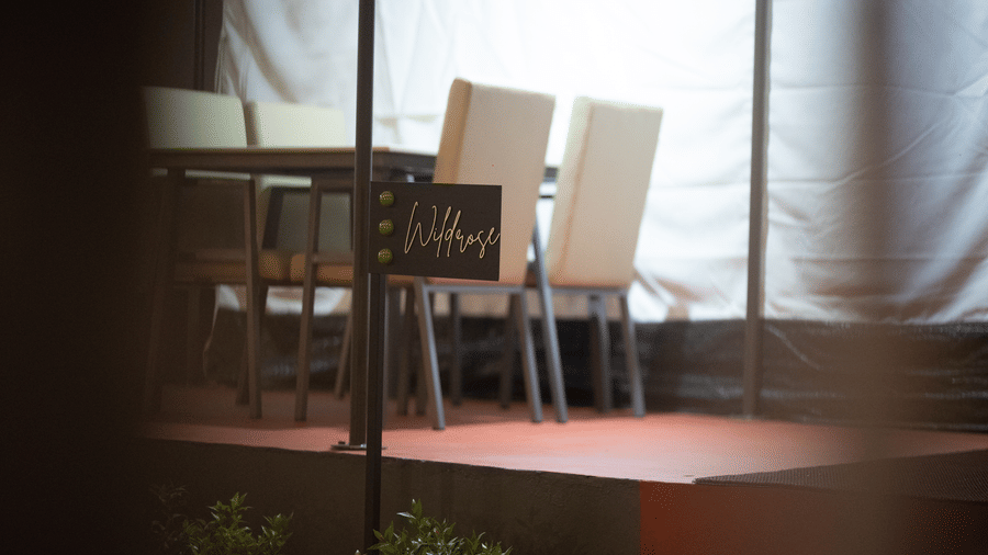 Intimate dining setup inside a tent featuring cream upholstered chairs and a modern dining table.