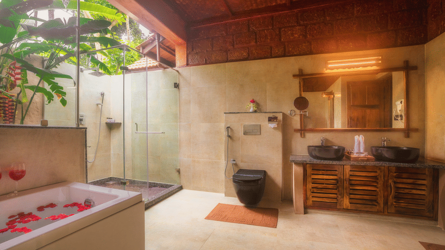 Oak Luxury Villa in Coorg at Copper Edge featuring bathtub across a vanity with 2 sinks and a large mirror with toiletries on the slab