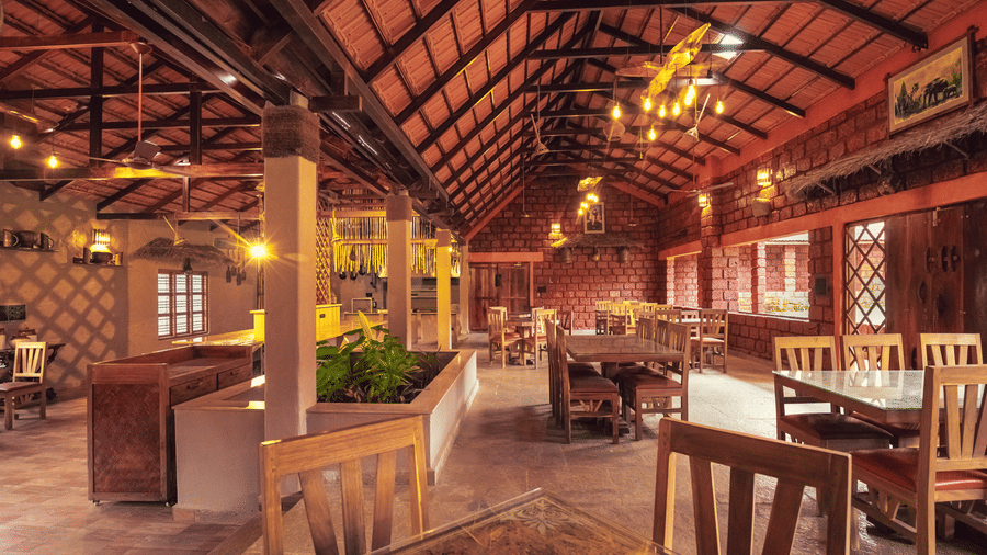A dining hall with a high wooden ceiling and many tables and chairs at Robasta, one of the best restaurants in Coorg, Madikeri