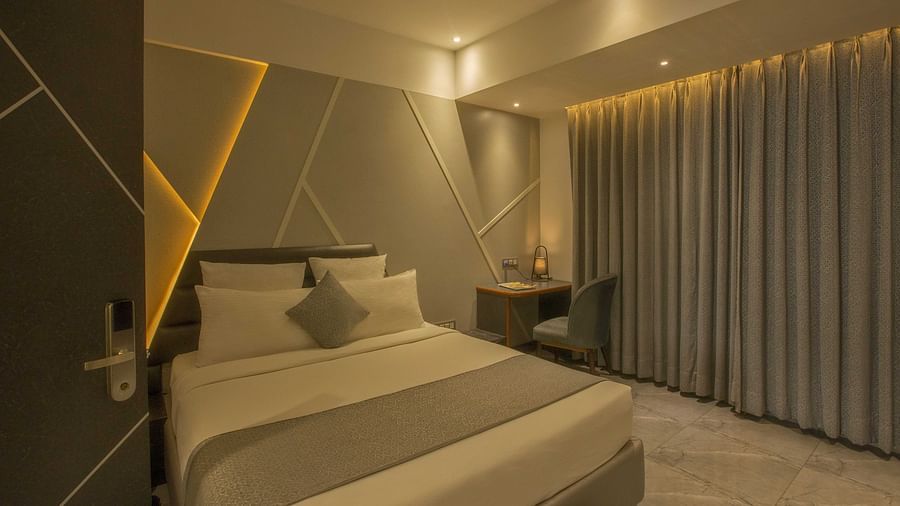 Image of well lit Coral Premium Room at Coral Reef Hotel and Spa in Port Blair featuring a plush bed and a work desk and chair next to it near the window
