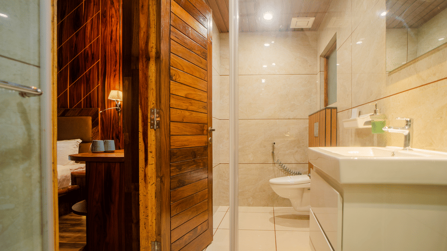 A modern bathroom with marble walls, a white sink, and a shower area. The clean design is complemented by bright lighting, giving the space a fresh and sleek look.