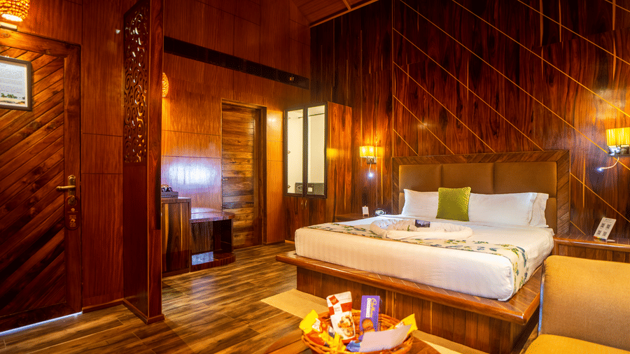  A hotel room featuring a wooden interior with warm lighting, a comfortable bed with pillows, and stylish fixtures. The space exudes a rustic and welcoming atmosphere.