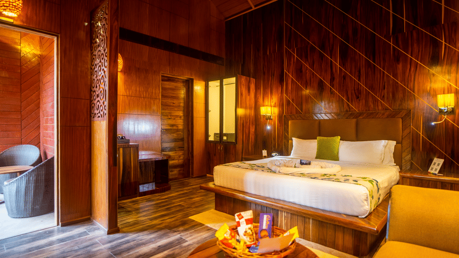 A wooden-themed room with a large bed, a comfy seating area, and soft lighting. The design is cosy and rustic, offering a welcoming, relaxed atmosphere.