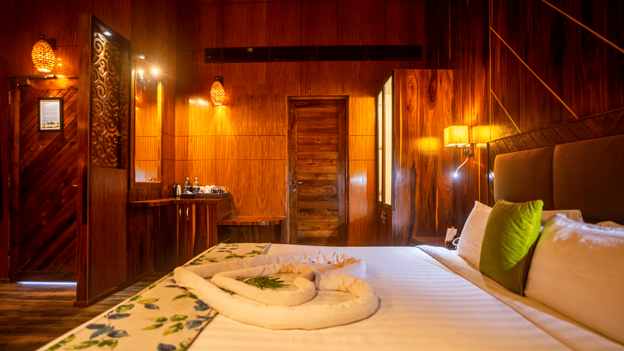 A hotel room with a large bed, wooden walls, and soft, ambient lighting. The room has a rustic charm, featuring comfortable furniture and decorative elements.