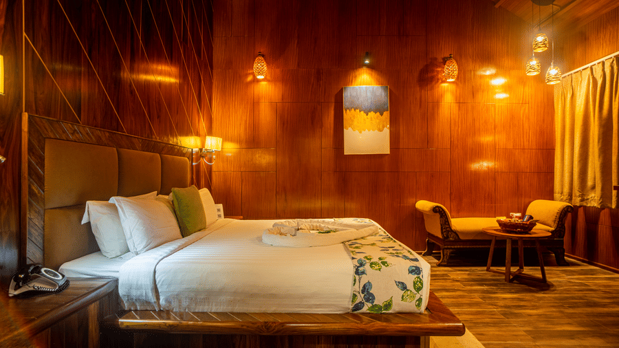 A serene wooden hotel room featuring a king-sized bed, comfortable seating, and warm lighting. 