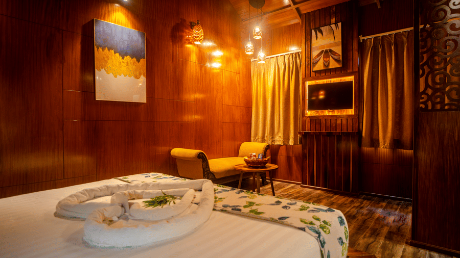 A beautifully designed wooden room featuring a large bed with soft linens, accent lighting, and stylish wooden furniture. The room has a serene and warm ambience perfect for a restful retreat.