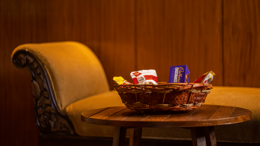  A side table with a small tray holding a cup and some snacks, placed in a room with wooden walls and a comfortable chair. The lighting is soft, creating a relaxing environment.