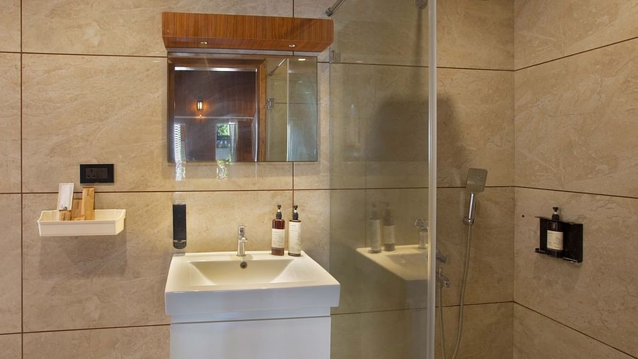 Image of the bathroom of Coral Azure at Coral Reef Resort and Spa in Havelock featuring a sink with toiletries placed and a mirror on the wall  next to which the shower space is separated with a glass door