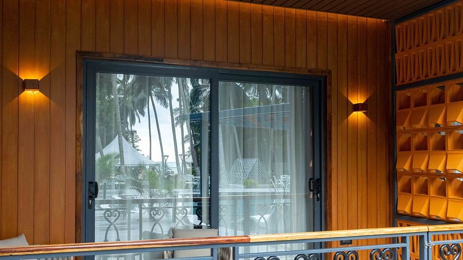Image of Coral Sapphire at Coral Reef Resort and Spa in Havelock featuring the glass door to outdoor seating area on the balcony with the reflection of the swimming pool and trees on the glass
