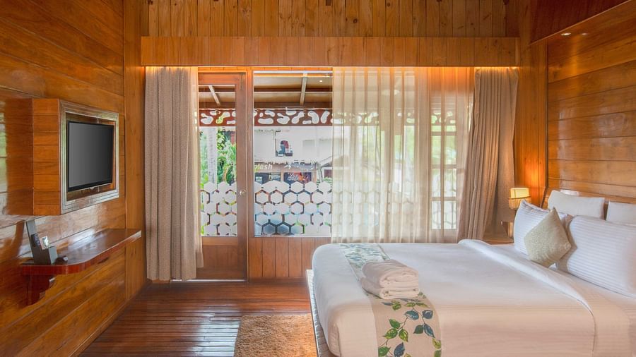 Image of Coral Turquoise at Coral Reef Resort and Spa in Havelock featuring a plush bed with a TV mounted on the wall in front of it and the doorway to the balcony