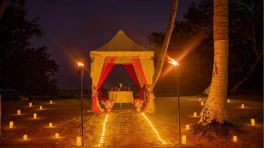 A canopy set up on a beach at night with a path of candles leading to it and torches on either side - Coral Reef Resort & Spa, Havelock