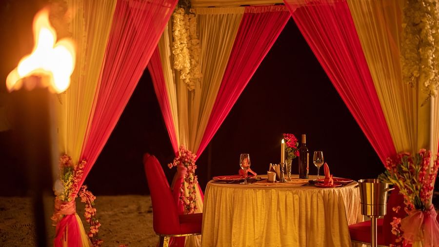 Inside view of a beach canopy with a dining table, lit by torches and surrounded by candles - Coral Reef Resort & Spa, Havelock
