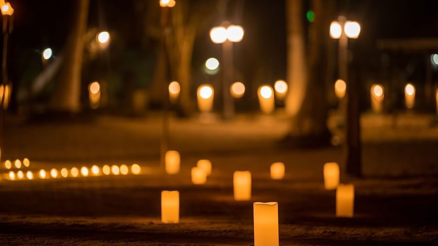 Illuminated candles on sand create a path at night with blurry lights in the background - Coral Reef Resort & Spa, Havelock