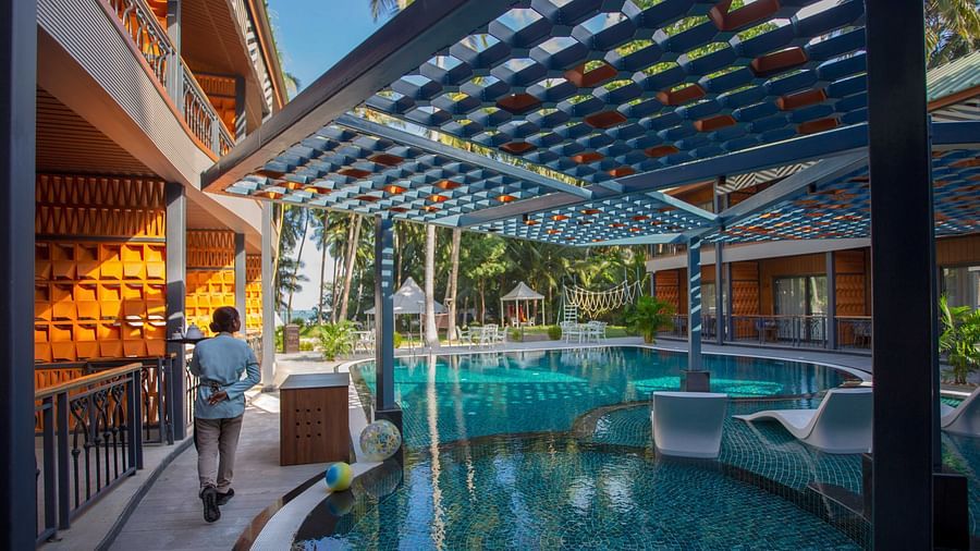 A stylish outdoor pool area featuring a modern wooden pergola and tropical plants. The pool is surrounded by comfortable seating and offers a relaxing environment - Coral Reef Resort & Spa, Havelock