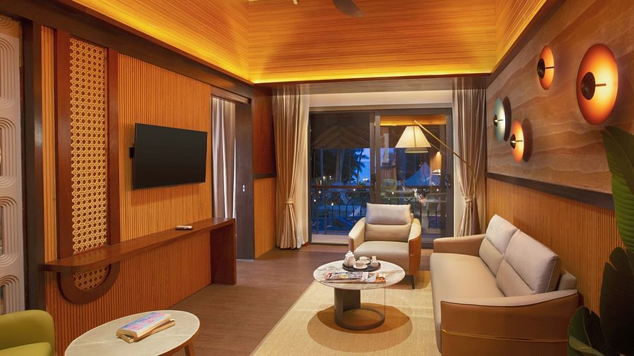 Image of the living room of Coral Teal Suite at Coral Reef Resort and Spa in Havelock featuring a sofa set placed around a coffee table facing the TV mounted on the wall and the doorway to the balcony in the background