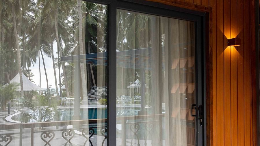 Coral Sapphire at Coral Reef Resort and Spa in Havelock displaying a shot of the glass door to the balcony with the swimming pool and trees reflecting on the glass