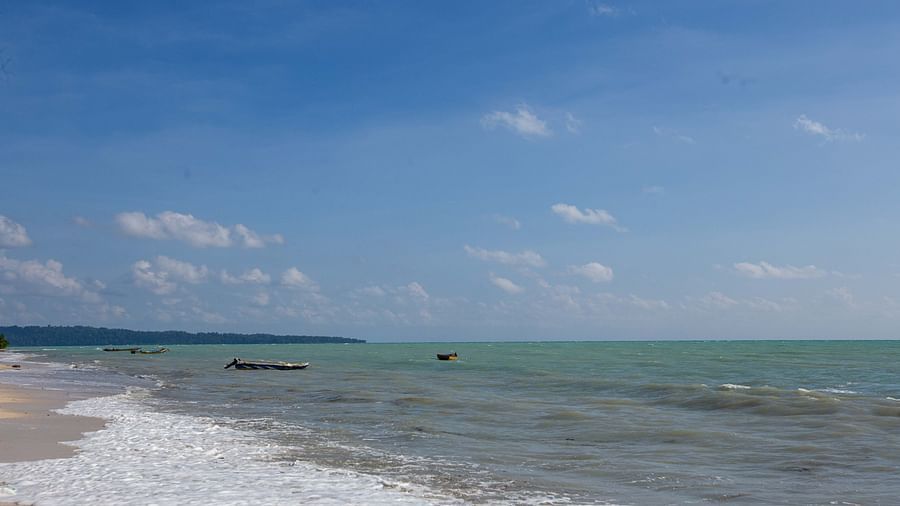A wide beach view with clear blue skies, calm waters, and a sandy shoreline. The tranquil atmosphere enhances the natural beauty of the environment - Coral Reef Resort & Spa, Havelock