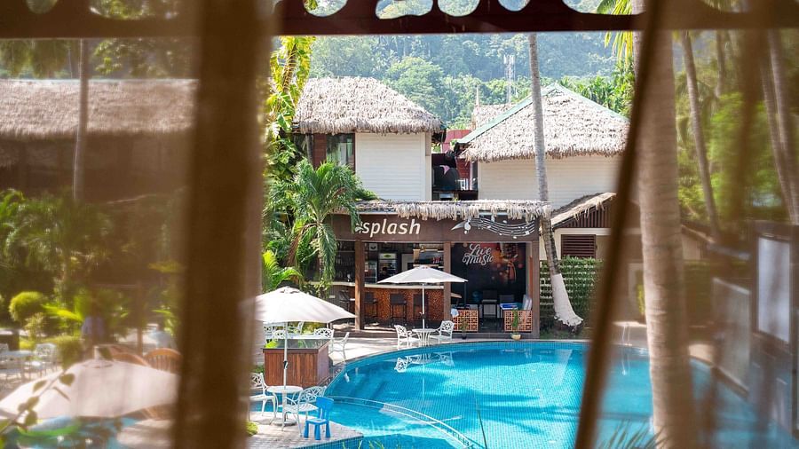  A poolside area with comfortable lounge chairs surrounded by tropical plants. The space is designed for ultimate relaxation, with clear, inviting water - Coral Reef Resort & Spa, Havelock