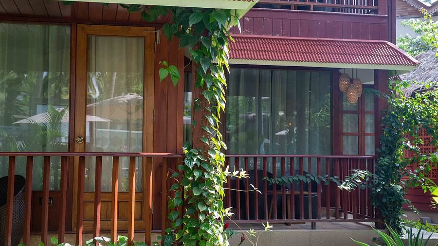 A view of a cozy balcony with a wooden railing, framed by lush greenery and vines. The space feels private and serene, offering a peaceful retreat - Coral Reef Resort & Spa, Havelock