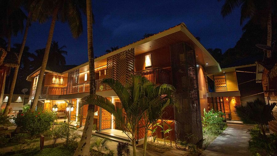  A beautifully lit exterior of the resort at night, with palm trees and warm lighting creating a welcoming ambience. The building has a rustic, tropical charm - Coral Reef Resort & Spa, Havelock
