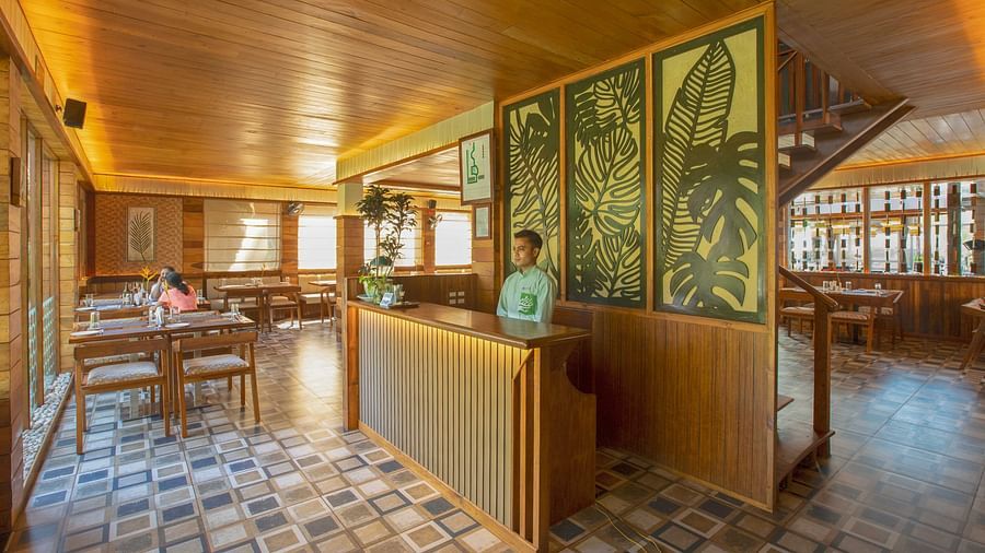 A modern restaurant with wooden interiors and a tiled floor. The dining area is well-lit, with large windows providing natural light and a pleasant, airy atmosphere - Coral Reef Resort & Spa, Havelock