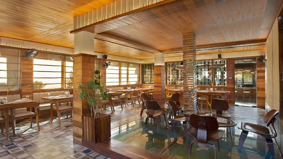 An elegant restaurant interior of Ocean Prime with wooden beams and tasteful decor. The space features a combination of dining tables and tropical plants, creating a warm, inviting vibe - Coral Reef Resort & Spa, Havelock