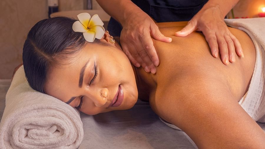  A woman receiving a soothing massage, surrounded by soft lighting and fresh flowers. The calm setting helps create a peaceful, spa-like experience - Coral Reef Resort & Spa, Havelock