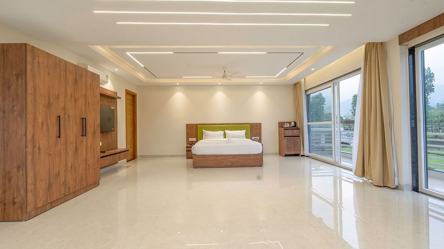 view of a king size bed and a wardrobe inside the suite at Corbett Four Seasons, Ramnagar