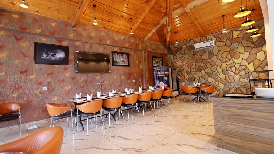 Dining area featuring warm lighting, rustic interiors, and comfortable chairs at Corbett Nirvana Resort.