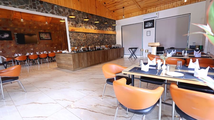 Restaurant with wooden ceiling, stone walls, and modern seating at Corbett Nirvana Resort.