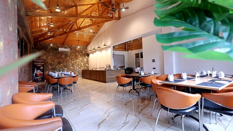 Stylish restaurant with high wooden ceiling and elegant decor at Corbett Nirvana Resort.