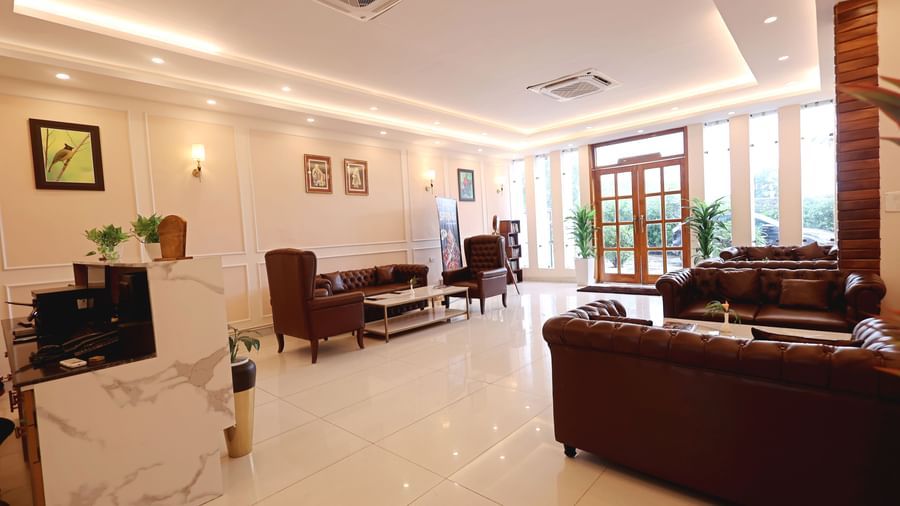  bright, spacious lobby with floor-to-ceiling windows and plush leather seating at Corbett Nirvana Resort.
