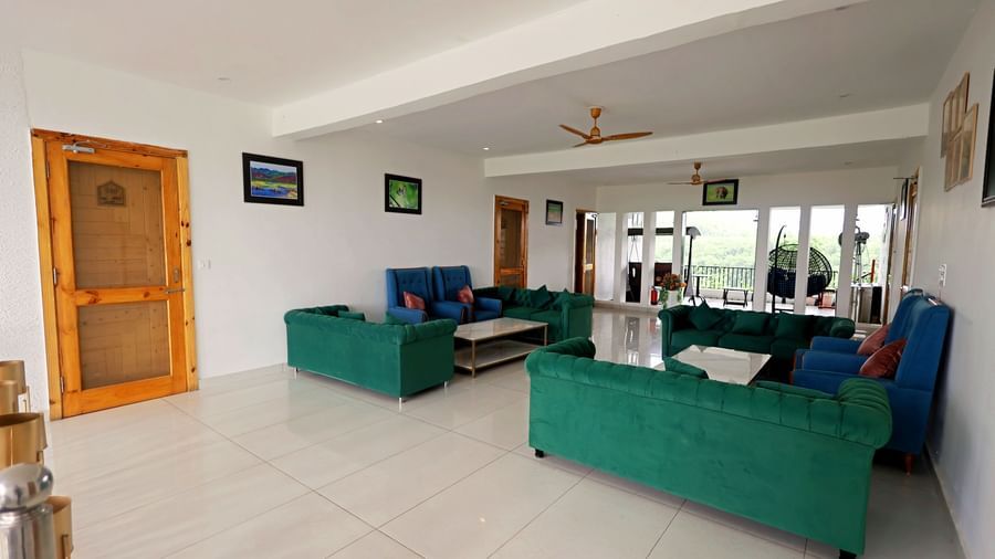 Lounge area with bright interiors, sofa seating, and modern design at Corbett Nirvana Resort.
