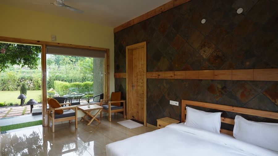 Spacious room with large windows, natural light, and cosy seating at Corbett Nirvana Resort.