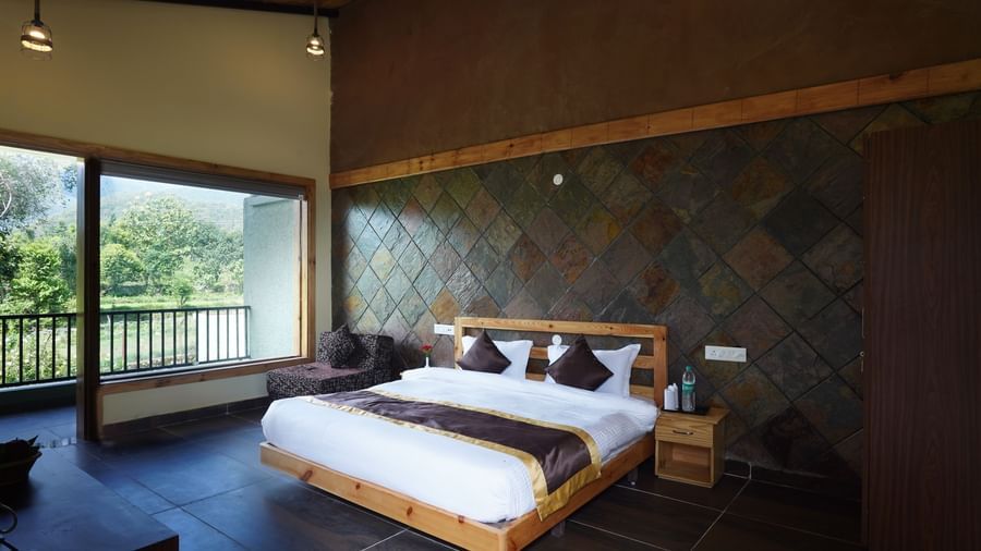 Premium resort room with stone wall accents and scenic outdoor views at Corbett Nirvana Resort.