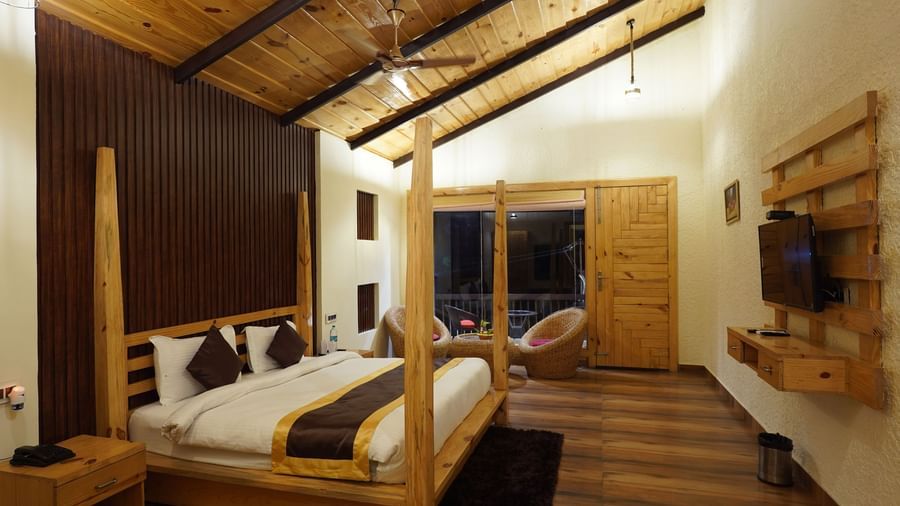 Rustic wooden-themed bedroom with modern furnishings and warm lighting at Corbett Nirvana Resort.