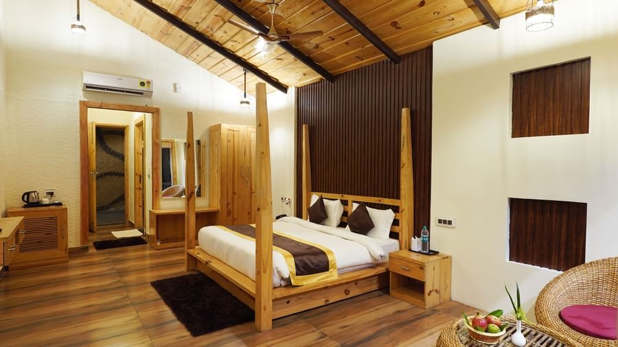 Stylish room with four-poster bed, wooden ceiling, and elegant interiors at Corbett Nirvana Resort.