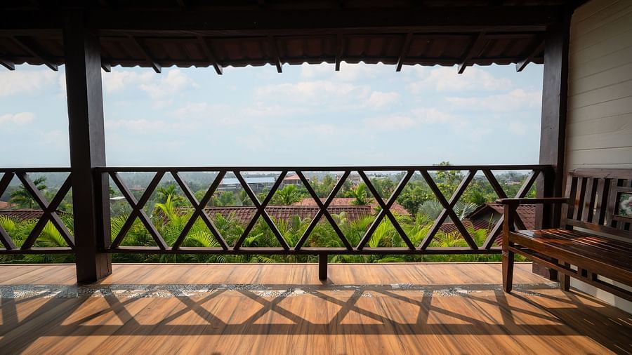Spacious balcony with wooden railings offering stunning views of lush greenery and blue skies, ideal for relaxation and enjoying nature