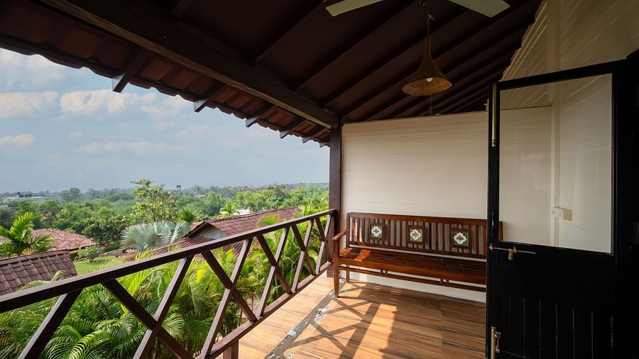 An image of a balcony with a lush view, shot from a corridor, and a fan in the shot.