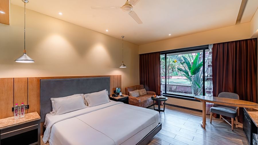 Club Room features a spacious bed, cushioned sofa, and a large window showcasing a natural view at Crescent Spa & Resort, Indore